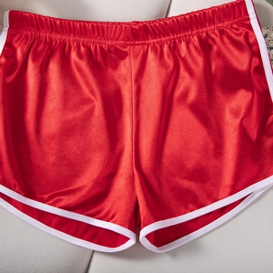 Detail of red satin sports shorts with white trim showing fabric texture and elastic waist