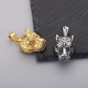 Close-up of gold and silver tiger head pendants with tribal engravings on stone