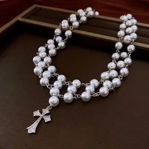 Double-layer pearl necklace featuring a zircon cross pendant on a luxury display tray