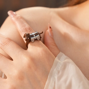 Detailed view of a brown dachshund ring with a silver rhinestone bow on the finger