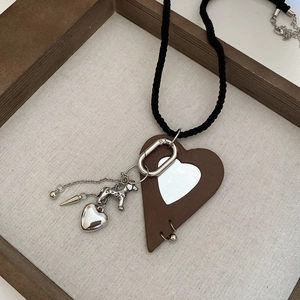 Detail of a dark brown leather heart pendant with silver dog charm and woven necklace
