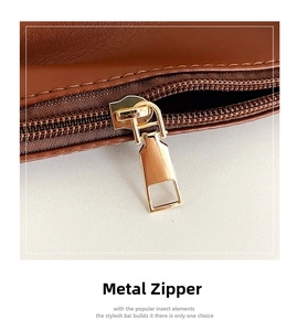 Detail of premium gold-tone metal zipper and precise stitching on brown suede tote bag