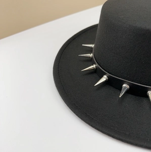 Macro detail of a black punk style wool felt fedora featuring sharp silver spike rivets