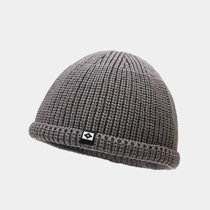 Gros plan d'un bonnet docker gris en tricot avec écusson logo N et texture côtelée
