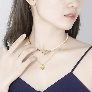 Double-layered gold necklace with heart pendant and pearls for women on model