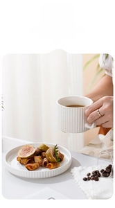 Detailed view of white ceramic coffee mug and saucer with vertical textured stripe pattern