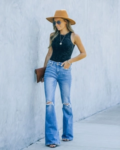 Vue street style d'un jean évasé taille haute avec genou déchiré et finition denim lavé