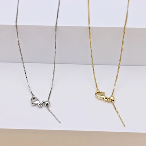 Detail of adjustable gold and silver box chains with slider beads and needle ends