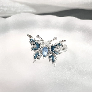 Makroansicht des silbernen Schmetterlingsrings mit blauen Emaille-Flügeln und Edelstein