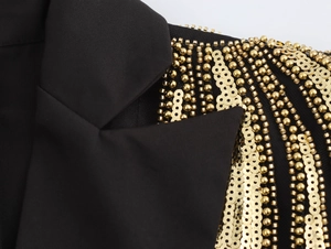 Detailed close-up of golden sequins and beadwork on the shoulder of a black blazer dress