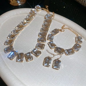 Luxe jewelry set featuring gold necklace, bracelet and earrings with square crystals