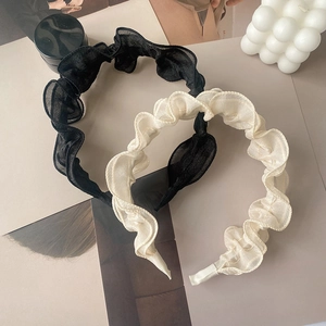 Elegant ruffled mesh headbands in black and cream white displayed with props