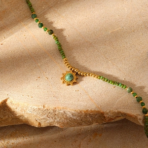 Bohemian beaded necklace with green stones and sun pendant on natural sandstone block