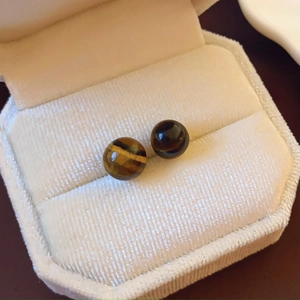 Close-up of brown tiger eye stone earrings in a premium velvet jewelry box