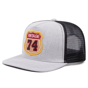 Detail of vintage 74 shield patch and black mesh breathable panels on trucker hat