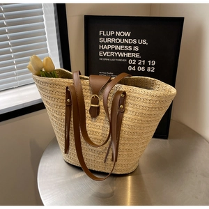 Detail of beige woven straw tote bag with brown PU leather strap and adjustable metal buckle