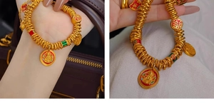 Detailed view of the 24k gold-plated cuff featuring Zirconia, Fu charms and enamel pendants