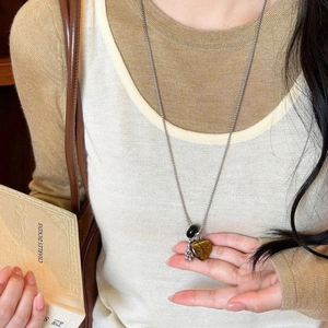 Tiger eye heart pendant necklace with stainless steel chain shown on model in vintage style