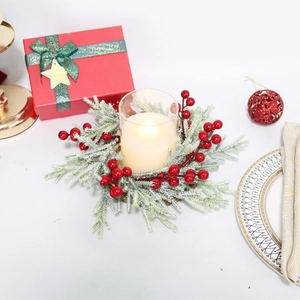 Detail of frosted pine needles and red berries wreath with a clear glass LED candle holder