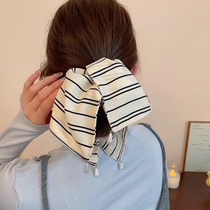 Détail d'une pince à cheveux à nœud rayé avec perles blanches dans un cadre élégant
