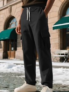 Detail of black corduroy cargo pants featuring elastic drawstring waist and side pockets