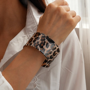 Close-up of wide leopard print acrylic cuff bracelet worn on a white shirt sleeve