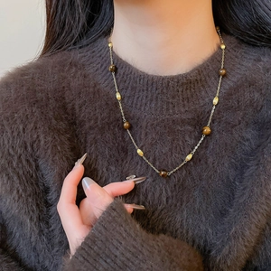 Detail of vintage tiger eye stone pendant necklace on a brown sweater background
