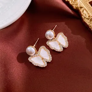 Elegant gold plated butterfly earrings with pearls and zircons on red silk background