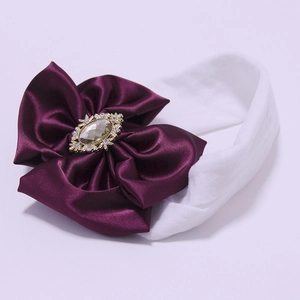 Baby nylon headband with a large purple satin bow and sparkling gemstone center