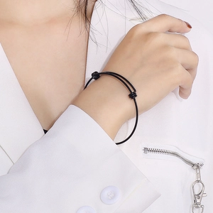Minimalist black adjustable stainless steel coil bracelet on a white suit jacket sleeve