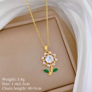Detail of gold floral pendant with zircon, pearls and green leaves on jewelry box