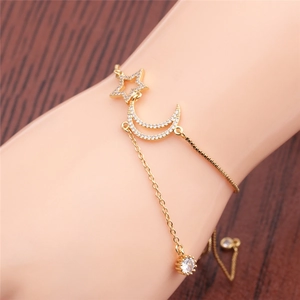 Detail view of gold star and moon bracelet with shimmering zircon stones on a wooden background