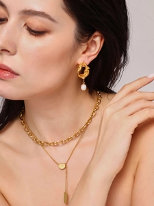 Gros plan détaillé de boucles d'oreilles dorées irrégulières avec perles d'eau douce
