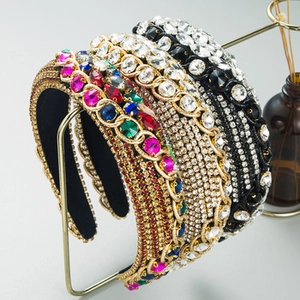 Detailed view of three baroque crystal headbands on a gold stand with gemstones