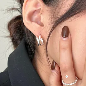 Close-up of minimalist S925 sterling silver knotted earrings and twisted ring on a model