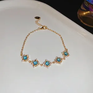 Elegant gold chain bracelet featuring five square blue zircons with sparkling diamond borders