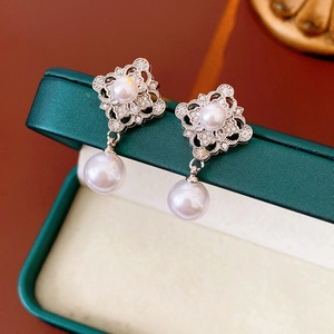 Close-up of vintage hollow silver earrings with pearls on a dark jewelry box