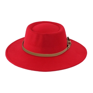 Detail of red wool felt fedora hat featuring a brown leather band and gold metal buckle