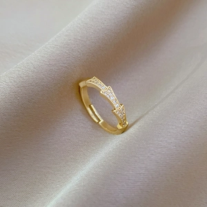 Close-up of golden bamboo-style zircon ring on silk background with adjustable opening