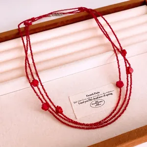 Vintage red beaded layered necklace with floral charms on a wooden jewelry display