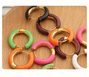 Macro shot of colorful round enamel earrings in various shades on a natural wooden background