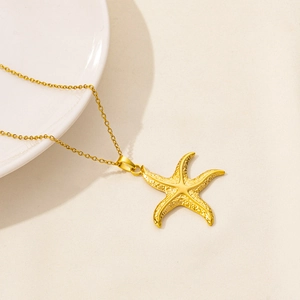 Golden starfish pendant necklace with detailed texture on a minimalist white background