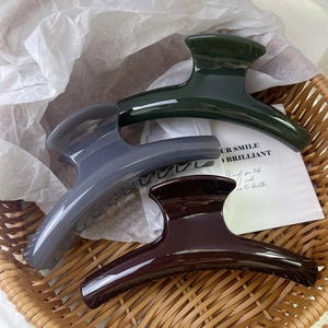 Three large matte finish hair claw clips in dark green, grey, and burgundy in a basket