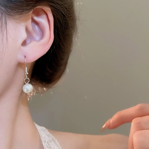 Close-up of elegant silver pearl earrings worn by a model for a sophisticated look