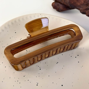 Close-up of brown faux wood grain square hollow hair claw clip on a ceramic plate