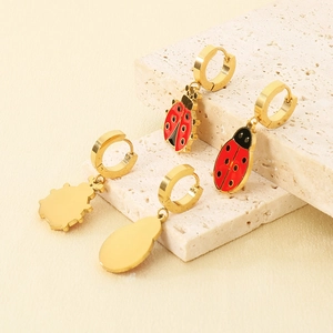 Detailed view of gold-plated ladybug earrings displayed on a natural textured stone base