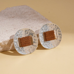 Detail of silver oval earrings with hammered texture and brown pleated fabric inlay