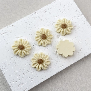 Detail of five cream resin flower charms with knitted texture for DIY phone case crafts