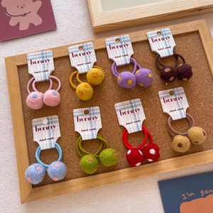 Detail of colorful children's hair ties with double pom-poms on a cork board