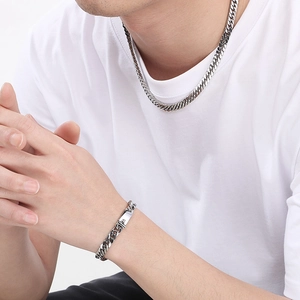 Close-up of polished stainless steel curb chain necklace and bracelet set on male model